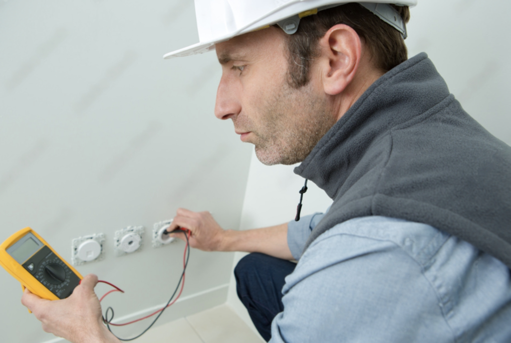 electrician testing electric socket with multimeter